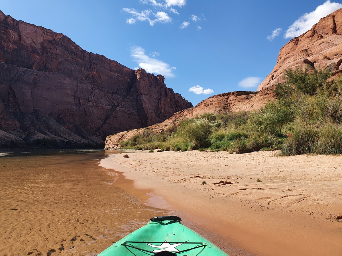 A green kayak beaching at a sandy shore in horseshoe Bend.