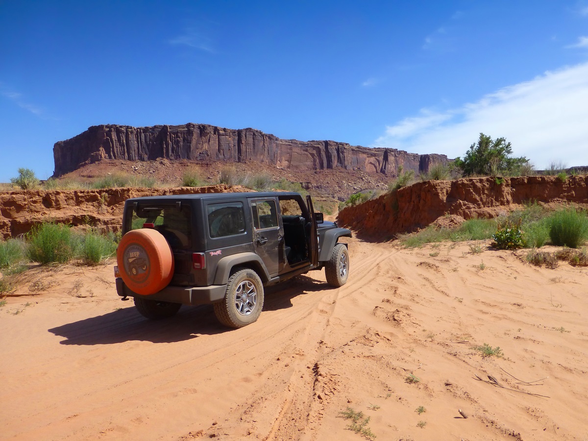 A jeep driving along soft sand along the White Rim Road.