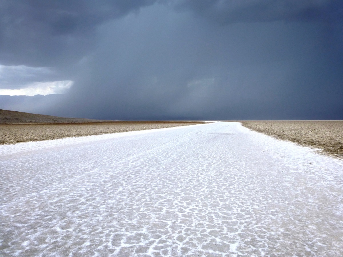 Salt flats at Death Valley, California with dark grey storms clouds in the distance.
