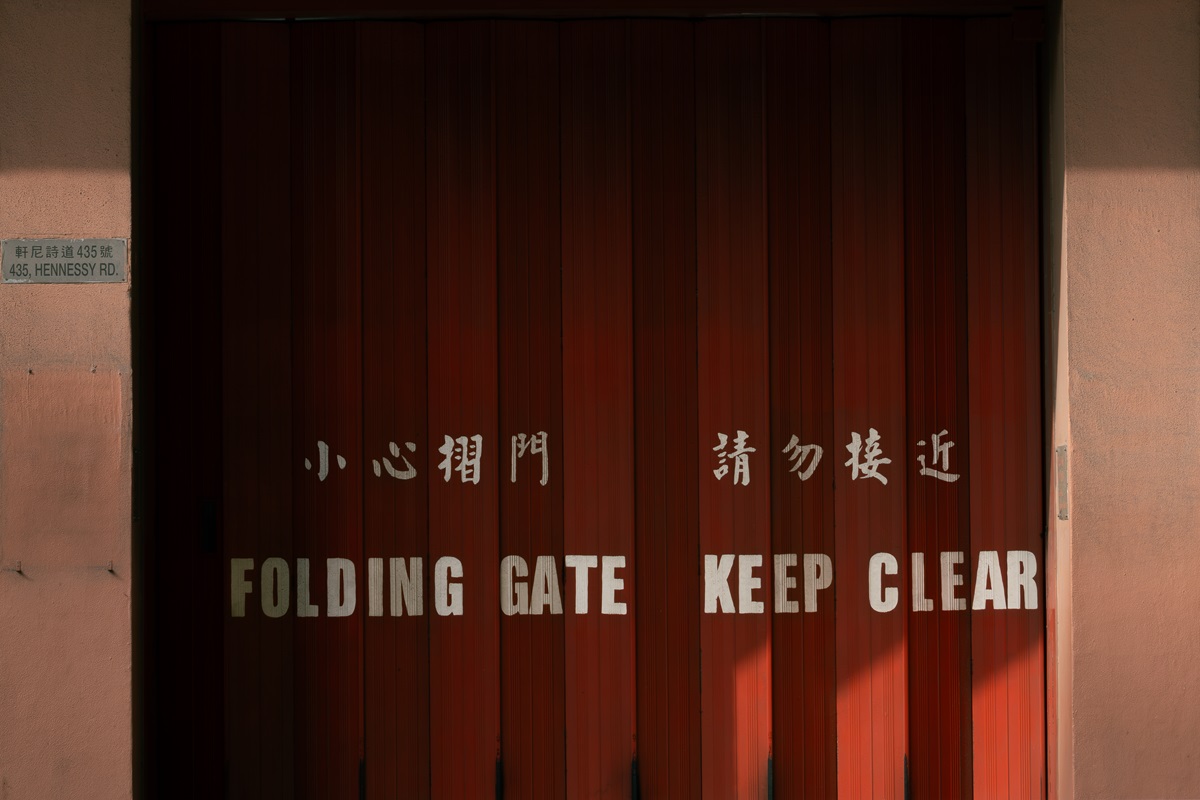 Writing on a garage door saying 'folding gate keep clear' in English and Chinese.