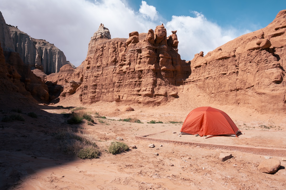 An orange tent between the sandstone walls at Goblin Valley State Campground in Utah.