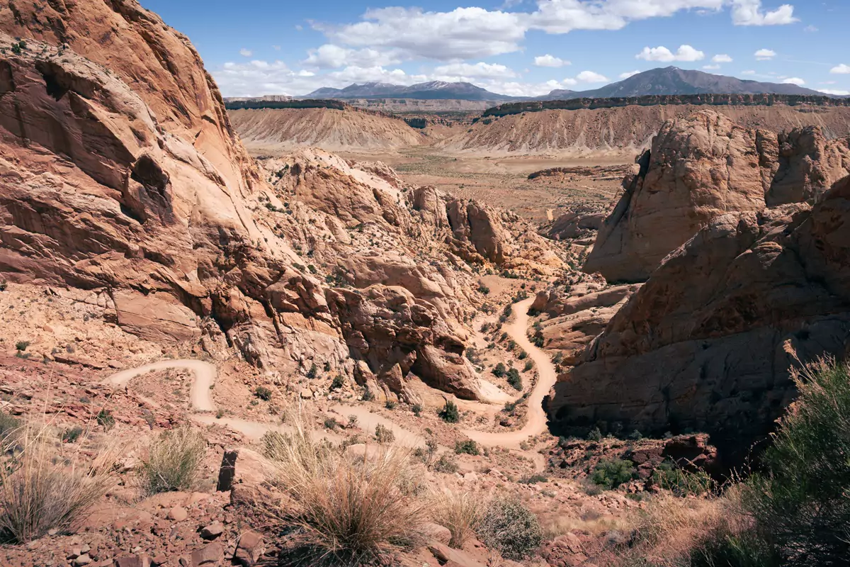 Road winding through a light coloured sandstone rock lined route at Capitol Reef's Burr Trail switchbacks.
