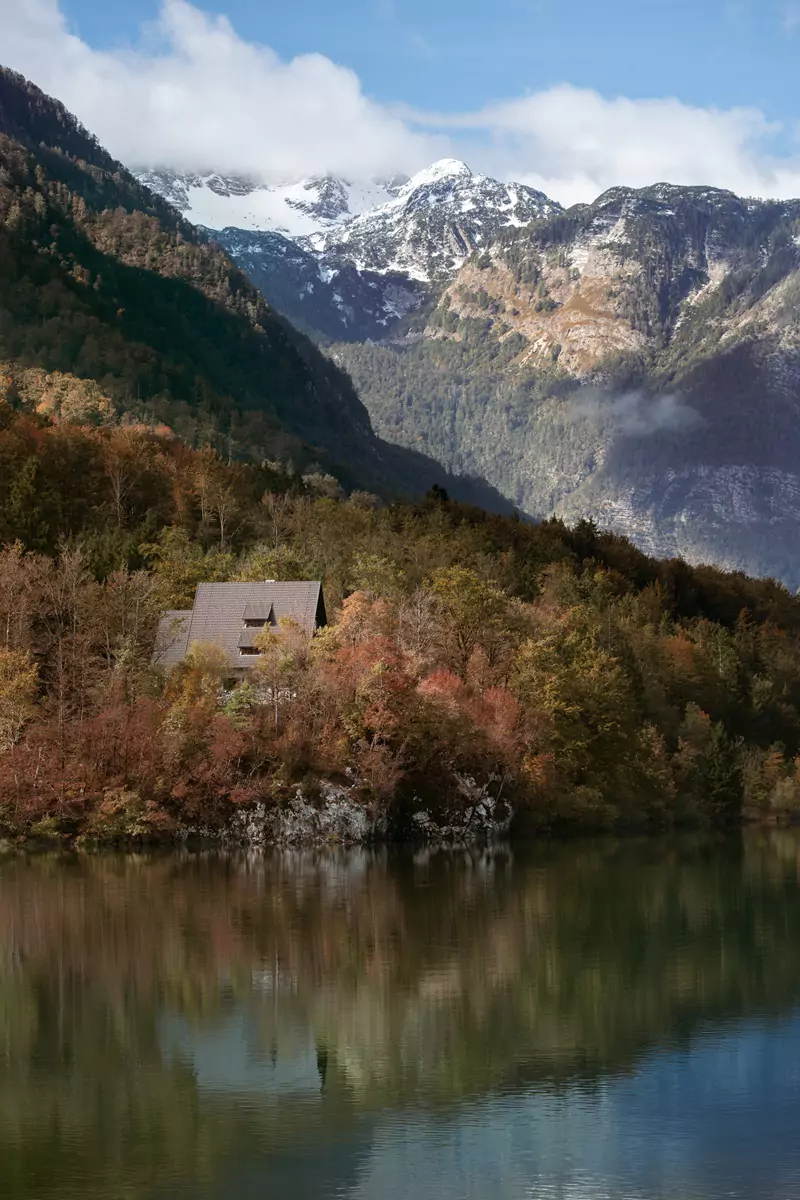 A house in the autumnal coloured trees beside Lake Bohinj in Slovenia.