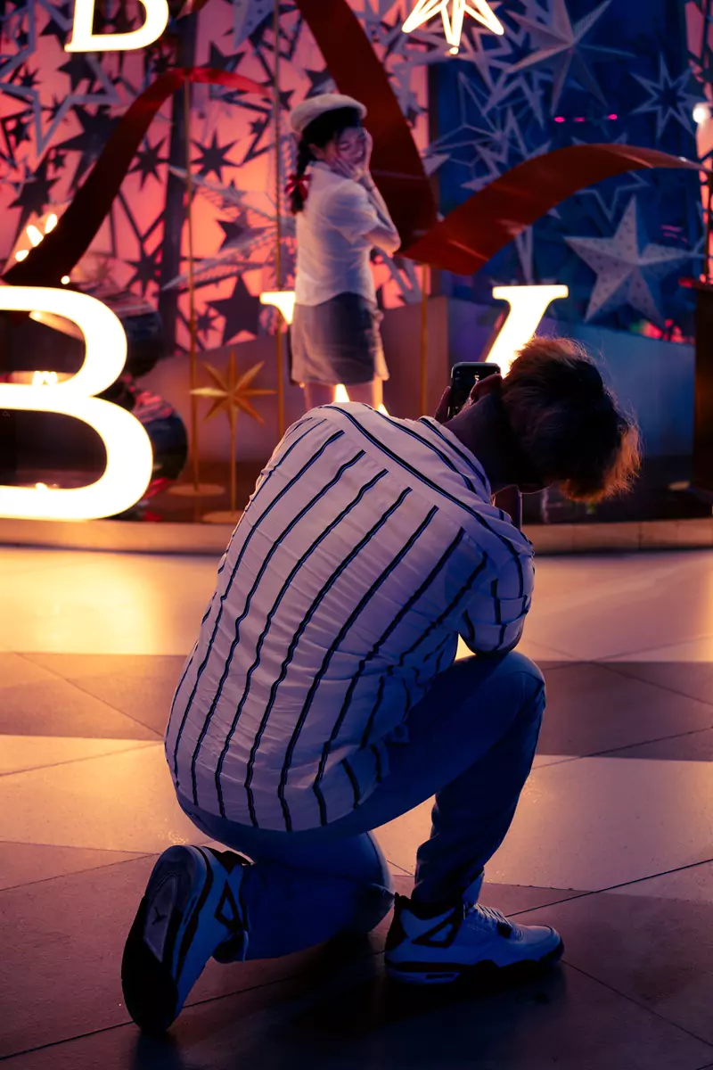 A photographer taking a picture of their child posing beside a Christmas display in a Bangkok mall.