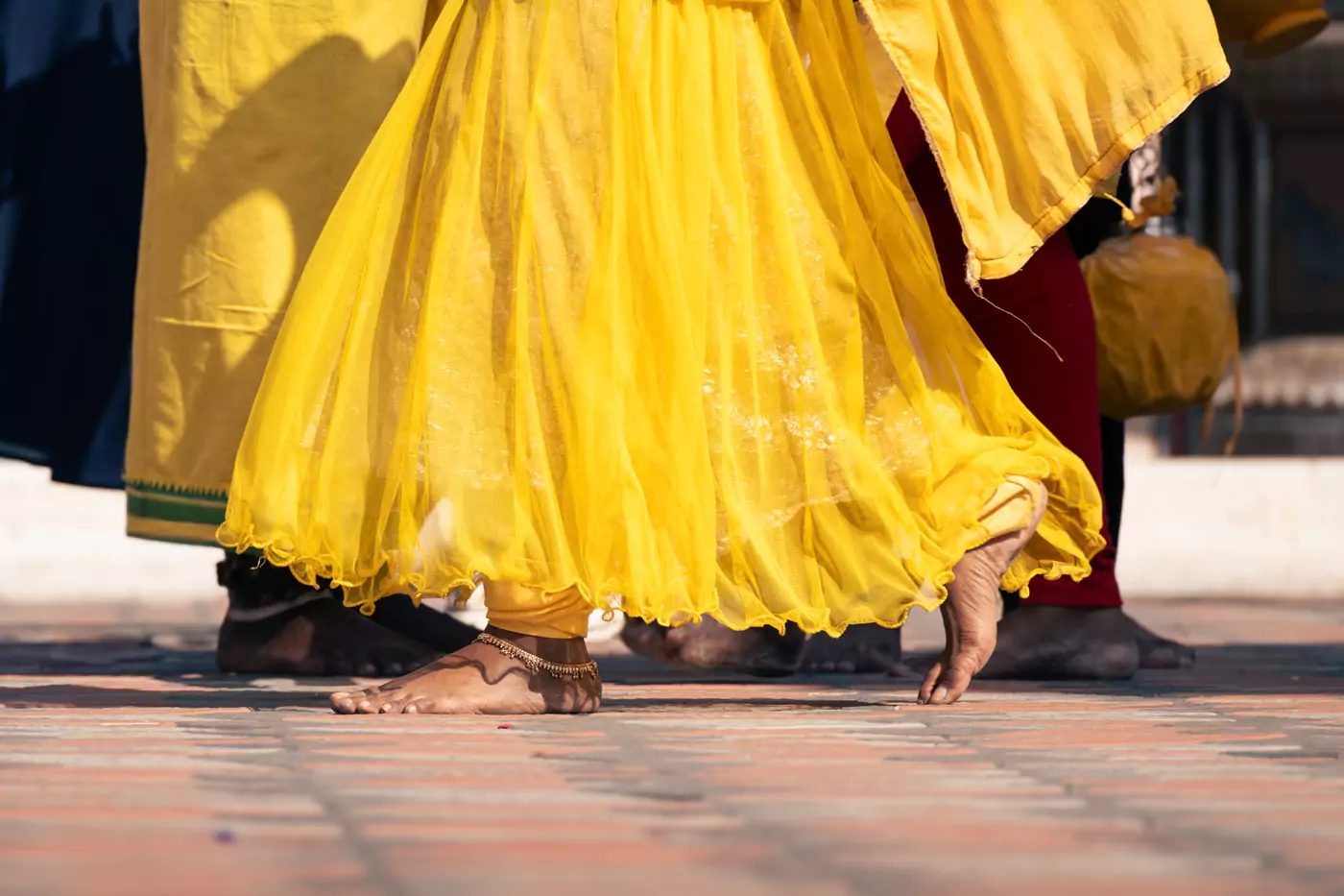 A devotee wearing a yellow dress and walking barefoot at Thaipusam in Kuala Lumpur.