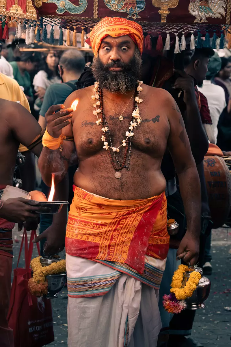 A devotee in a trance at Thaipusam, holding flames between their fingertips.