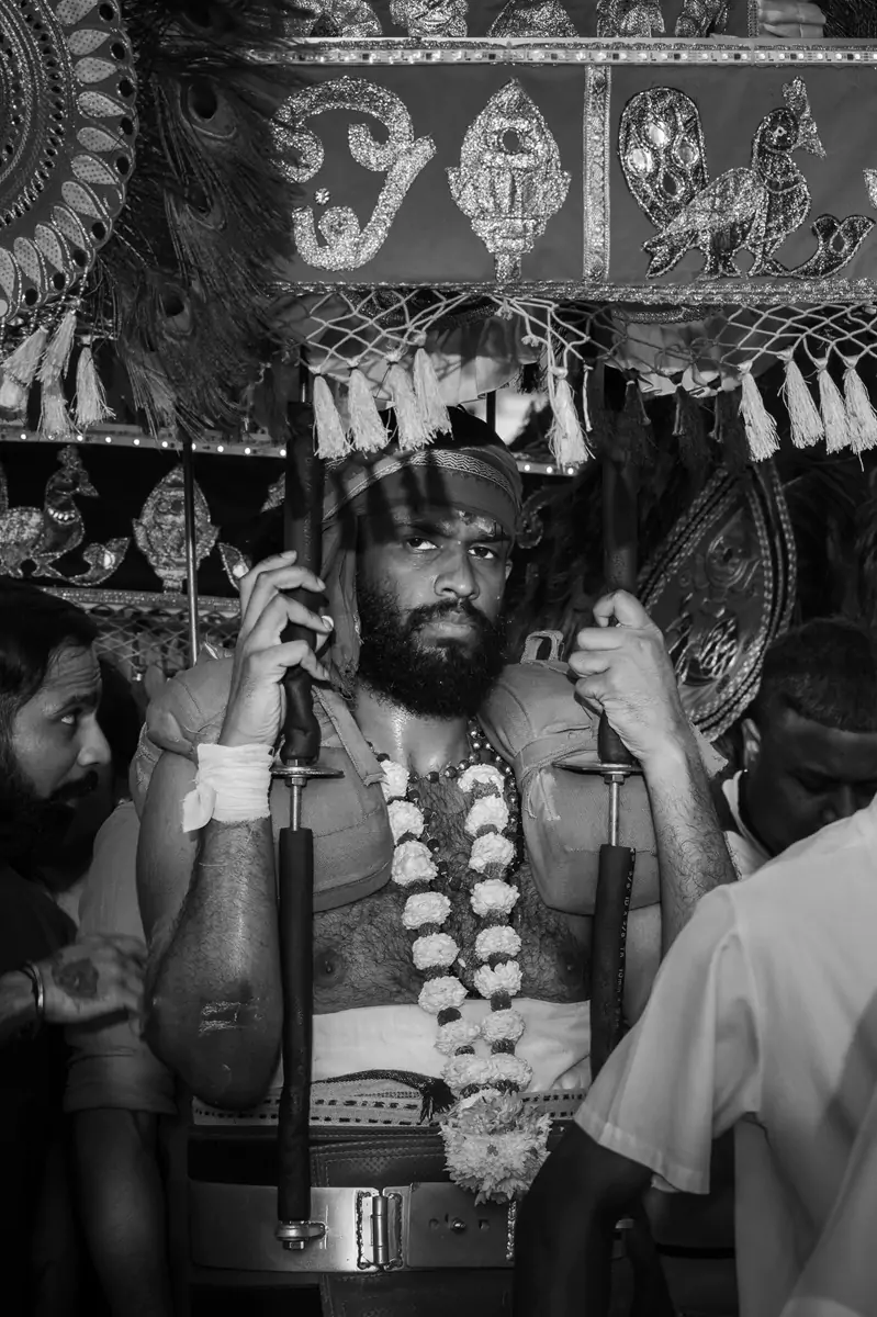 A kavadi wearer gripping onto their kavadi with both their hands as they wait in line during the Batu Cave's Thaipusam celebrations in Kuala Lumpur.