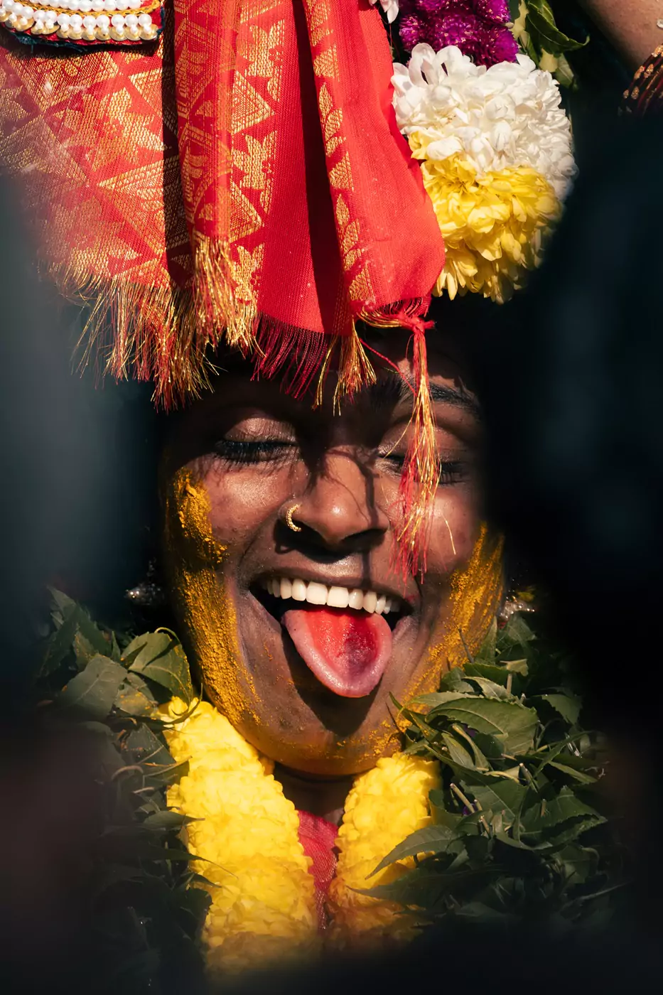A devotee at the Batu Caves' Thaipusam festival joyfully dancing while wearing a yellow flower garland.