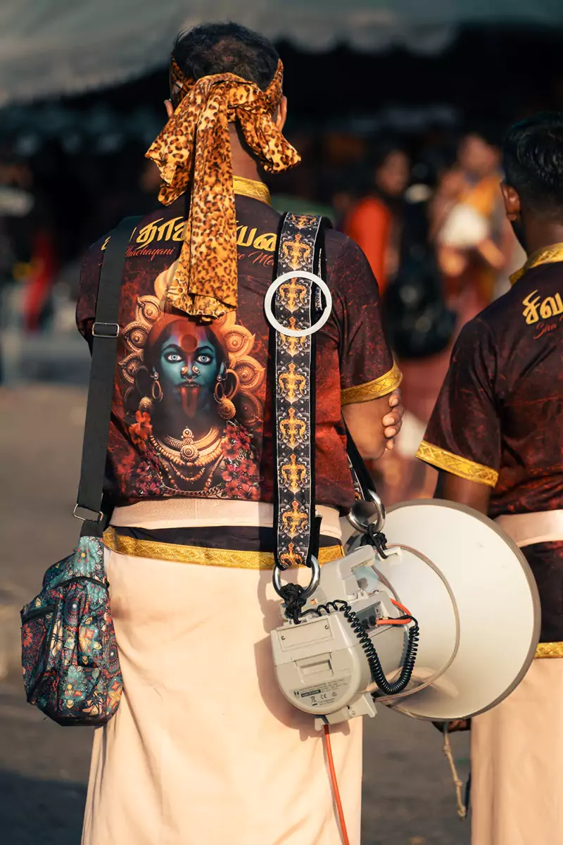A singer, using a megaphone, of a troupe supporting a kavadi wearer during Thaipusam at the Batu Caves.