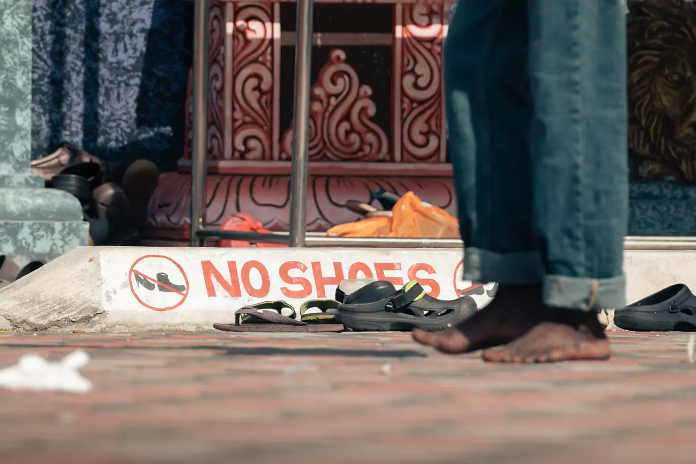 A painted sign saying 'No shoes' outside the temple at the batu Caves in Kuala Lumpur.