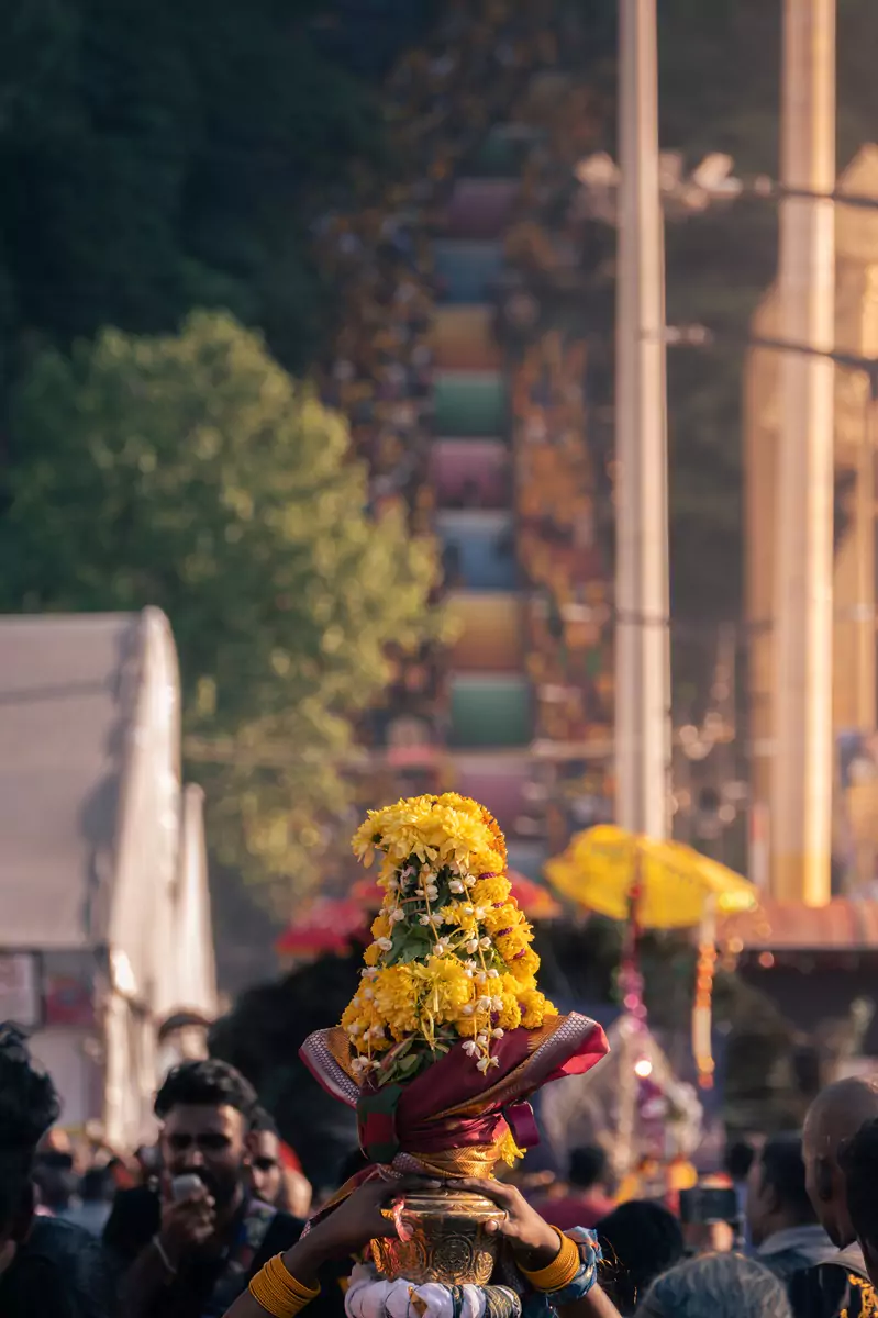 A paal kudam (milk pot) offering adorned with yellow flowers and leaves, sat atop a devotee's head on the way to the Batu Caves during the Thaipusam festival in Kuala Lumpur.