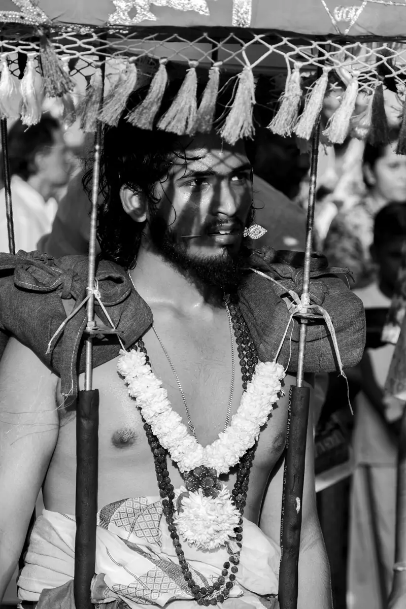 Shadows from the tassels of a kavadi on a garland wearing kavadi bearer's face at the Batu Cave's Thaipusam festival.