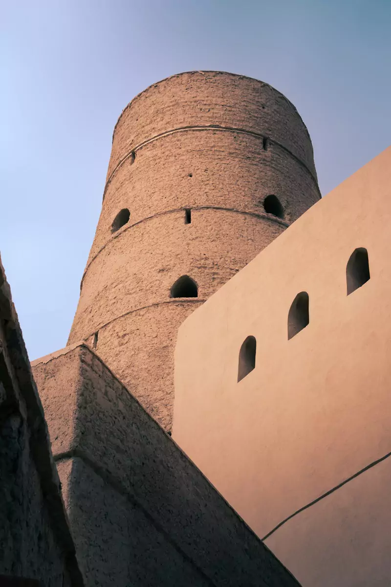 Tall circular tower and fortified walls at Bahla Fort near Nizwa, Oman.