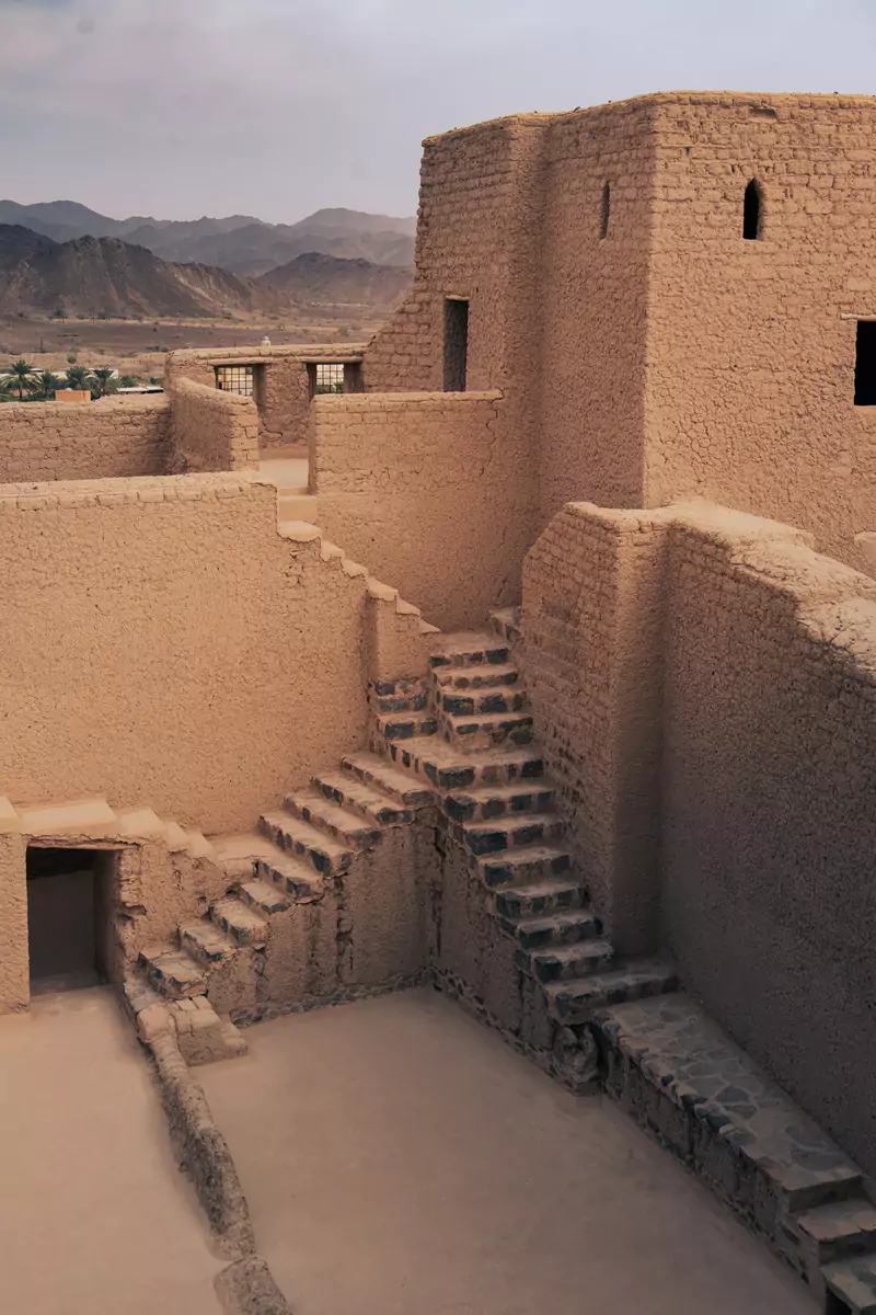 Mudbrick architecture inside the courtyard at Bahla fort, showing stone-laid stairs leading up the the upper level.
