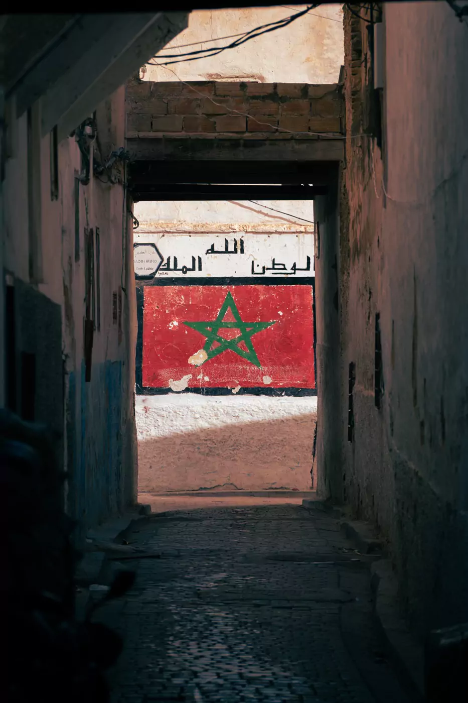 A Moroccan flag painted beneath Arabic writing on the walls of the medina in Fez.