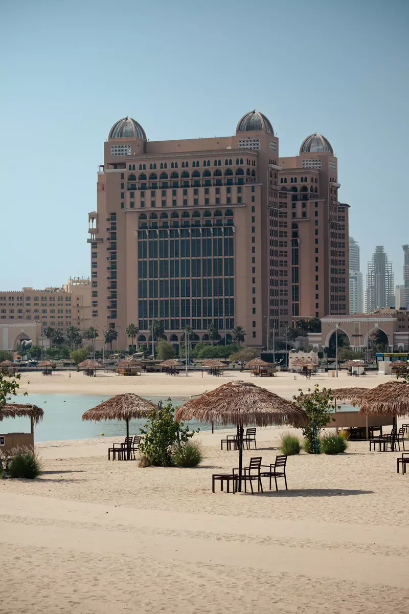 Woven parasols and beach chairs along the soft golden sands of Katara Beach in Doha, Qatar.
