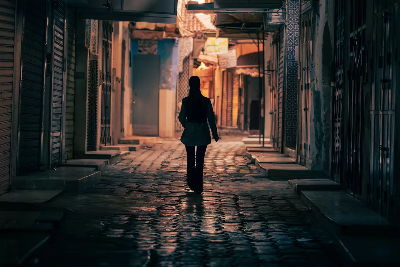 A person walking along the cobble streets of an alley in the medina of Meknes, Morocco.