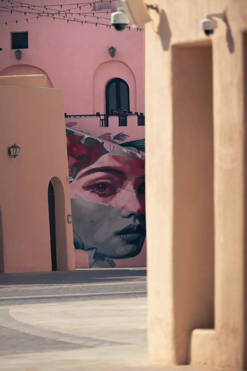 Street art on a building in the Mina district of Doha depicting a portrait of a woman's face.