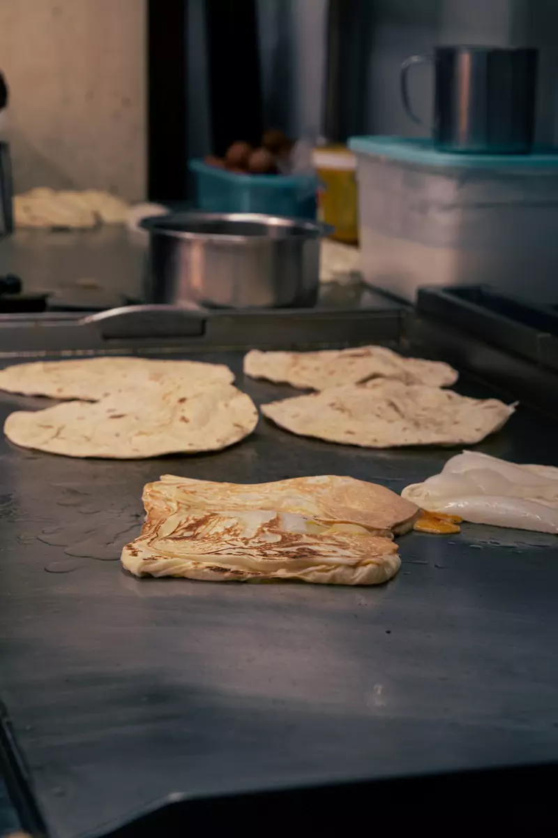 Various types of flat bread in different stages of being cooked in George Town, Penang.