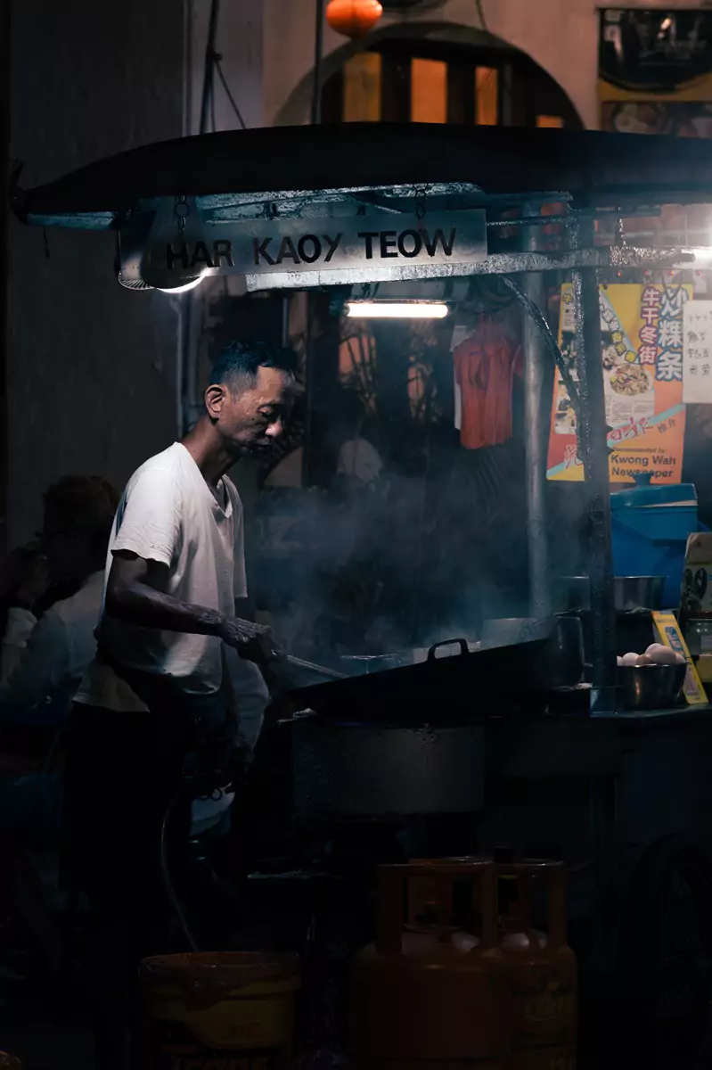 A food vendor frying food on the street in George Town, Penang.