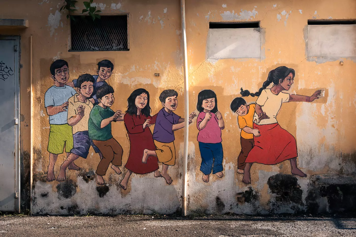A stencil style piece of street art in Mural Art's Lane in Ipoh of a group of children playing around.