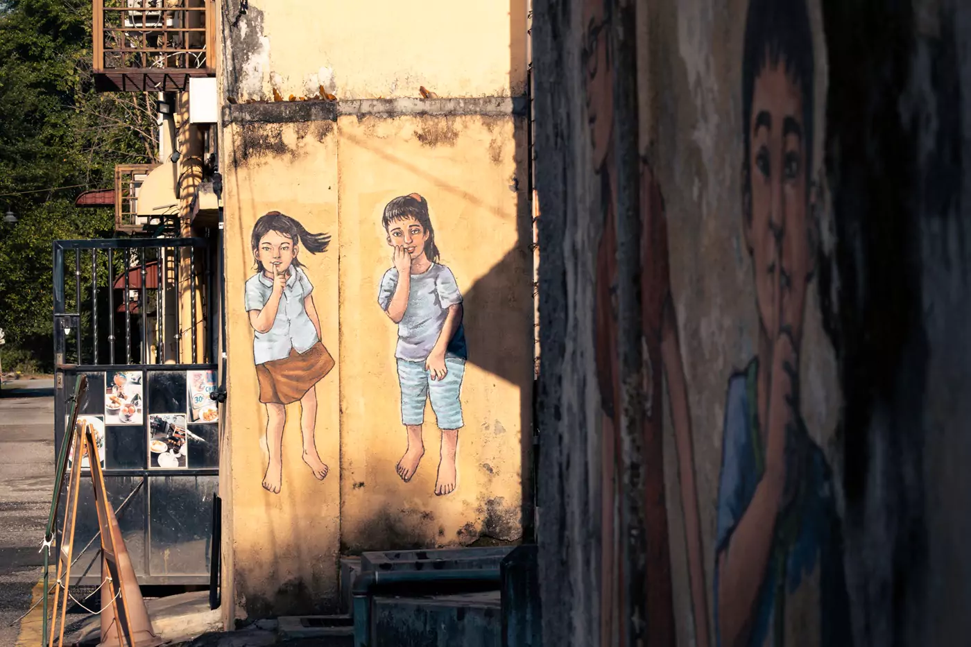 Mural street art in Ipoh, Malaysia, of some children playing hide and seek, telling the viewing to 'shh' so as not to give their location away.