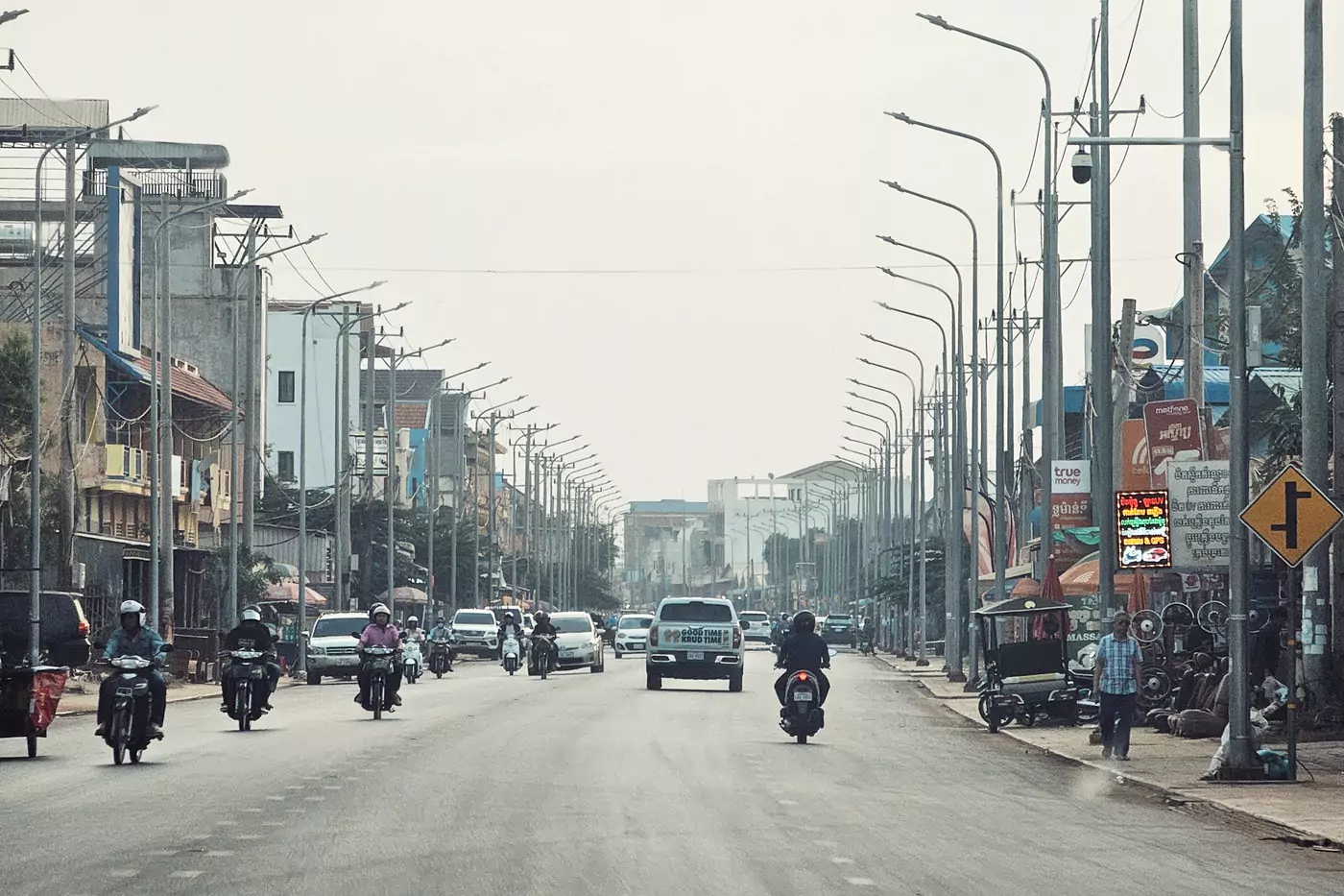 Cars and motorcycles driving along the wide roads in Siem Reap, Cambodia.