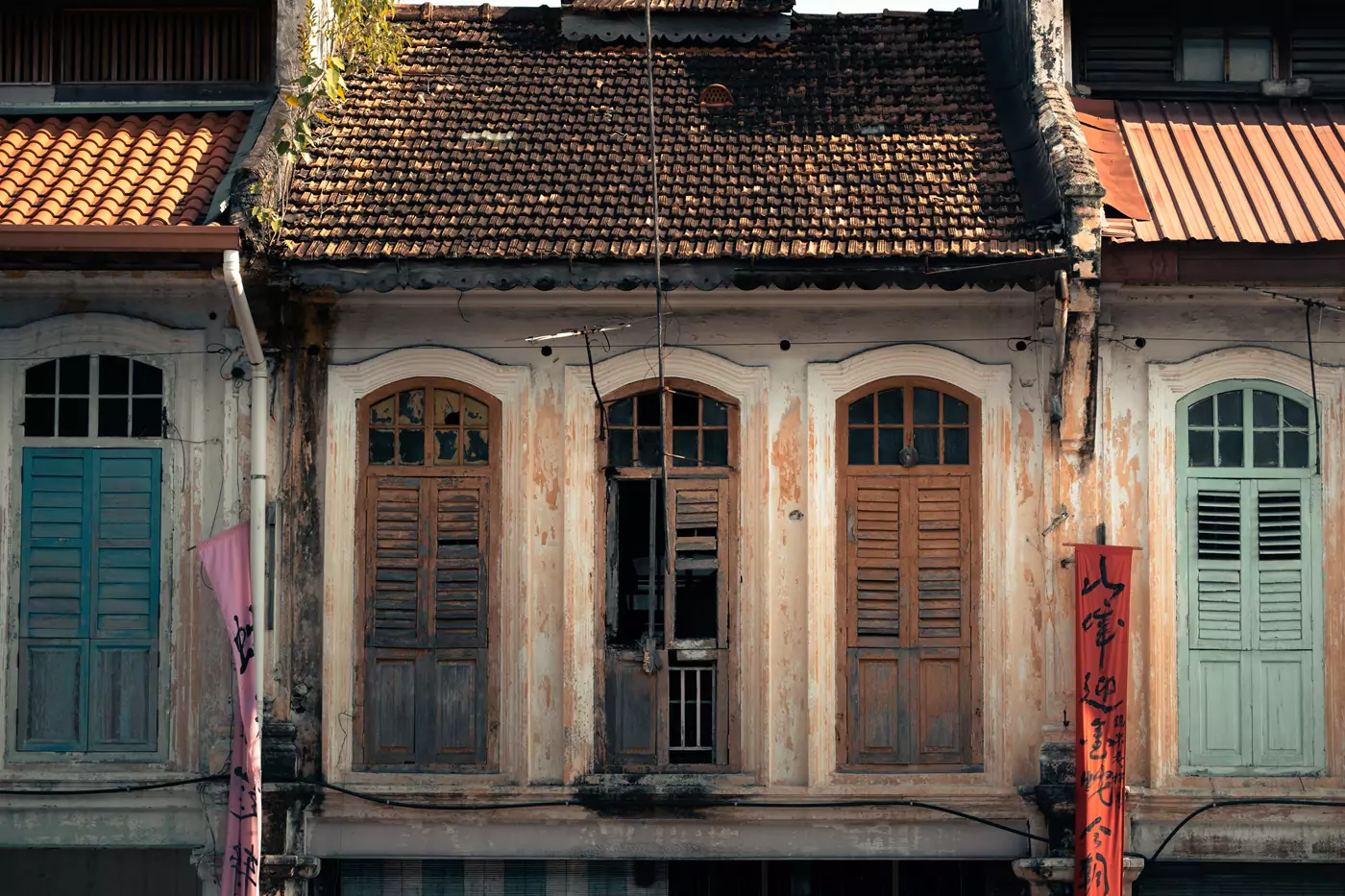 Broken wooden shutters on the window of a traditional home in old town Ipoh, Malaysia.