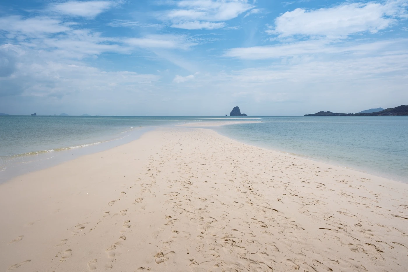Multiple sets of footprints in the soft sand of a spit at Laem Haad Beach.