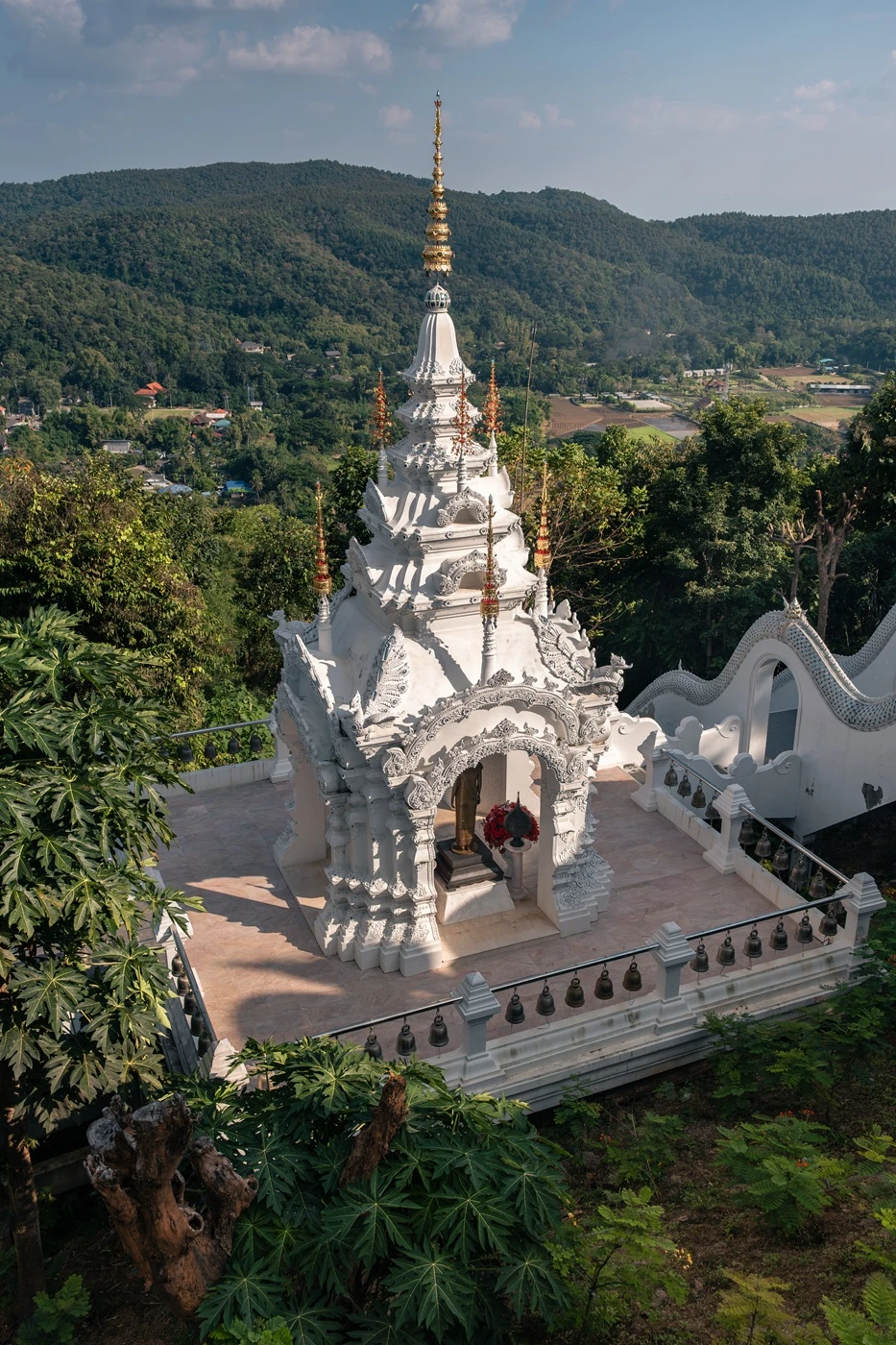 A white and gold stupa set beside a dragon staircase at Wat Pong near Chiang Mai, Thailand.