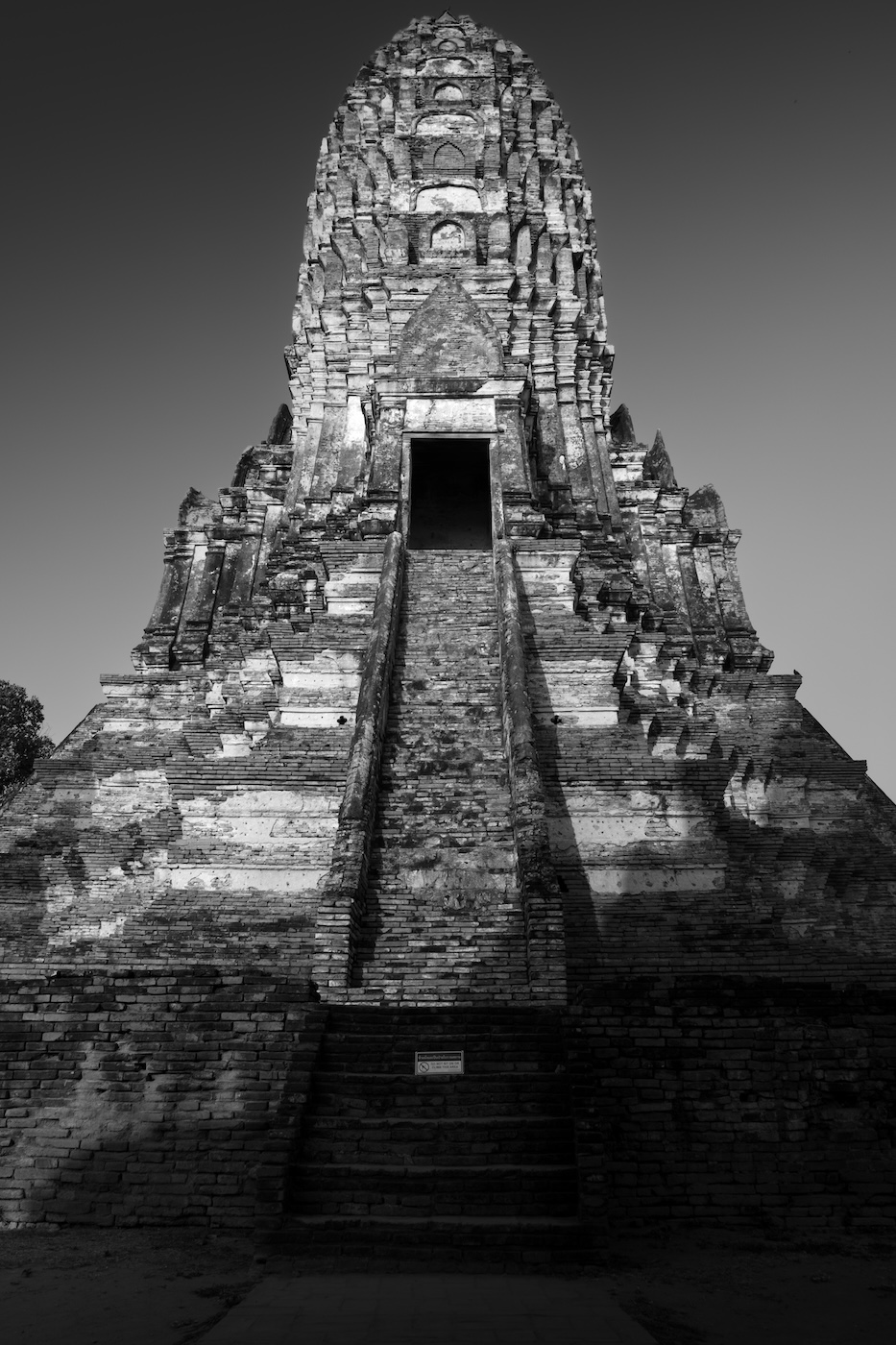 A black and white photo of stairs leading up to a prang tower at the ruins of Wat Chaiwatthanaram in Ayutthaya.