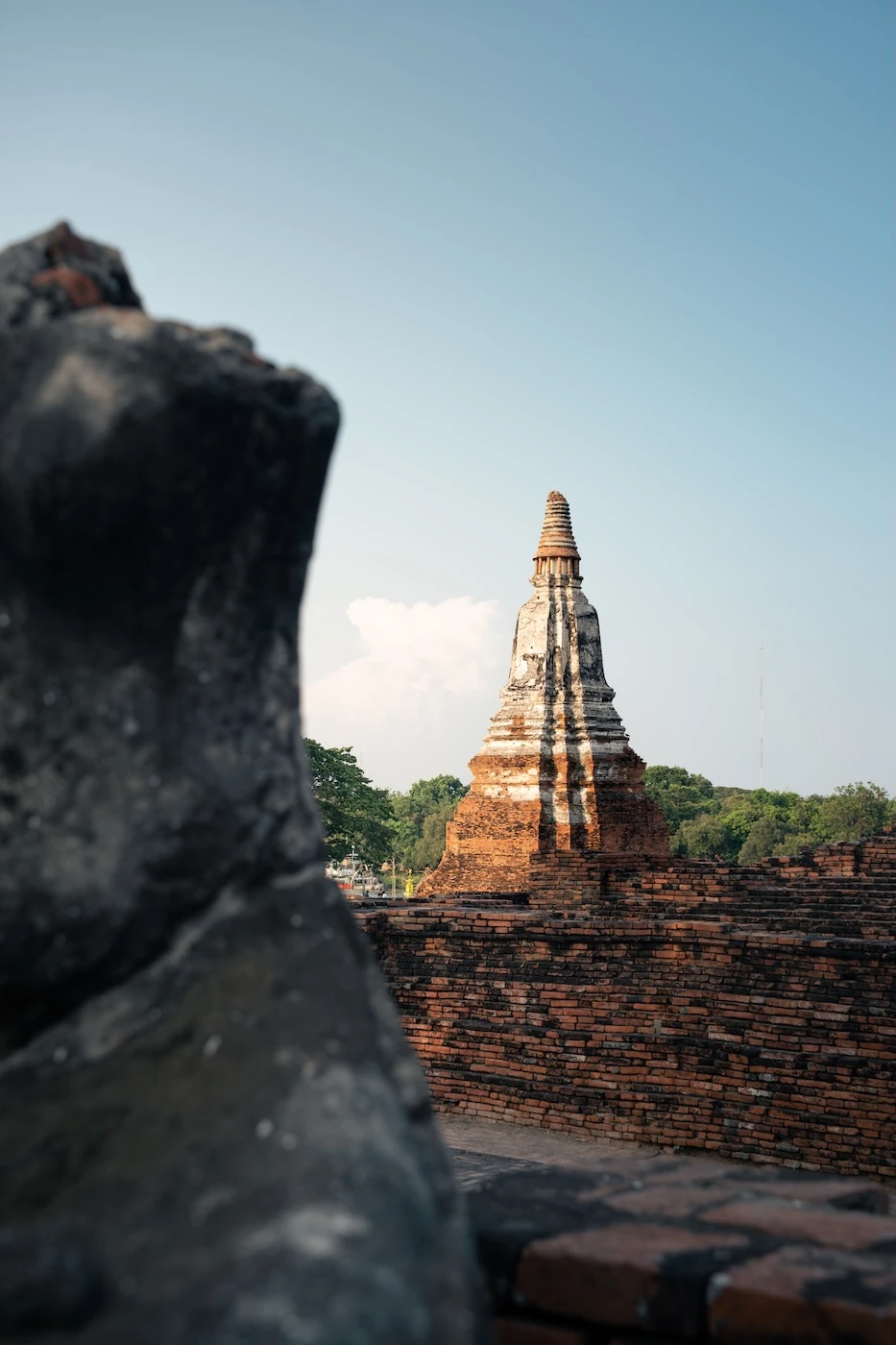 White and red brick built chedi behind the ruins of a red brick wall at Wat Chaiwatthanaram.