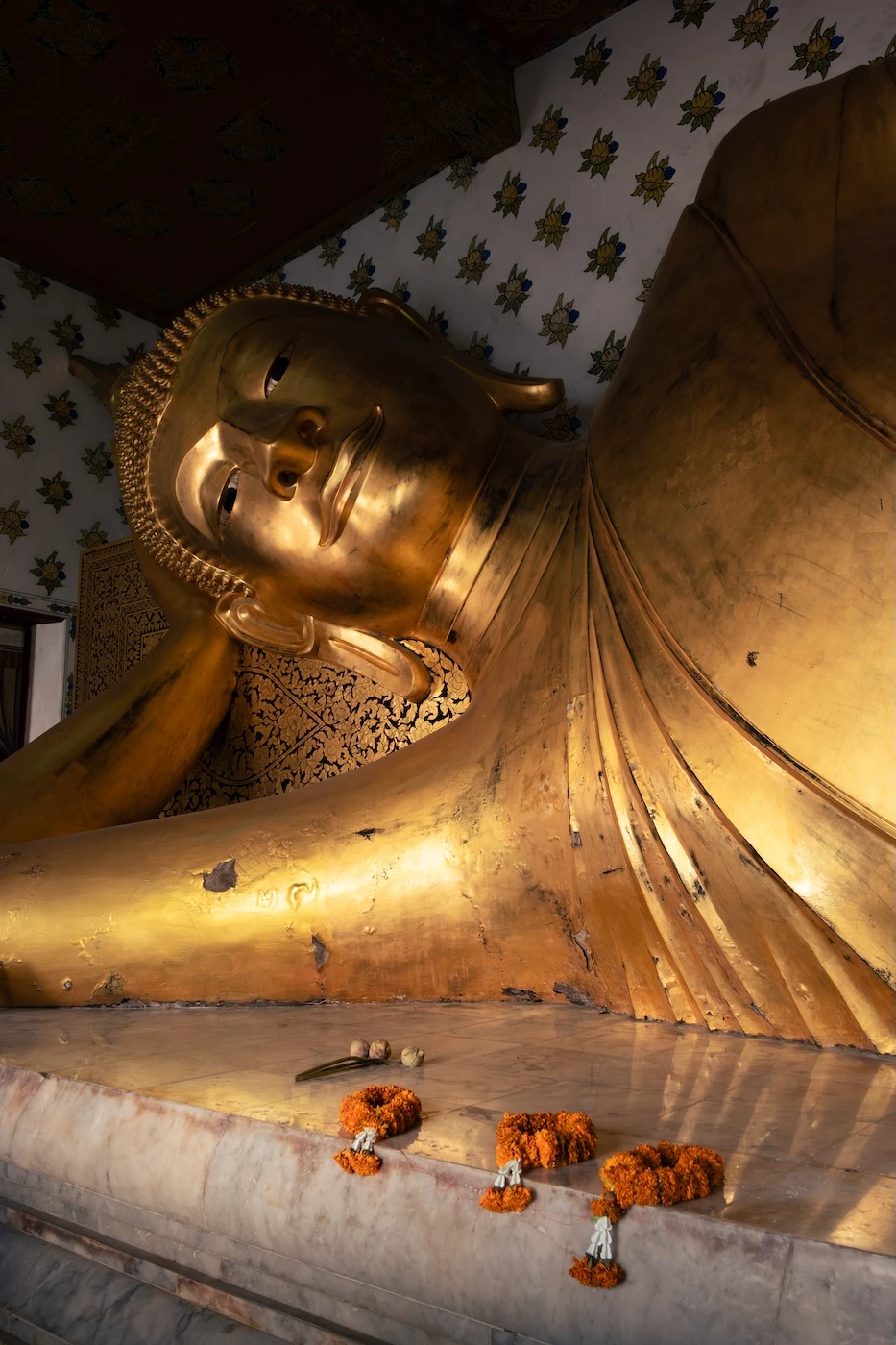 The head and torso of a reclining golden Buddha statue within a shrine at Wat Sensanaram.