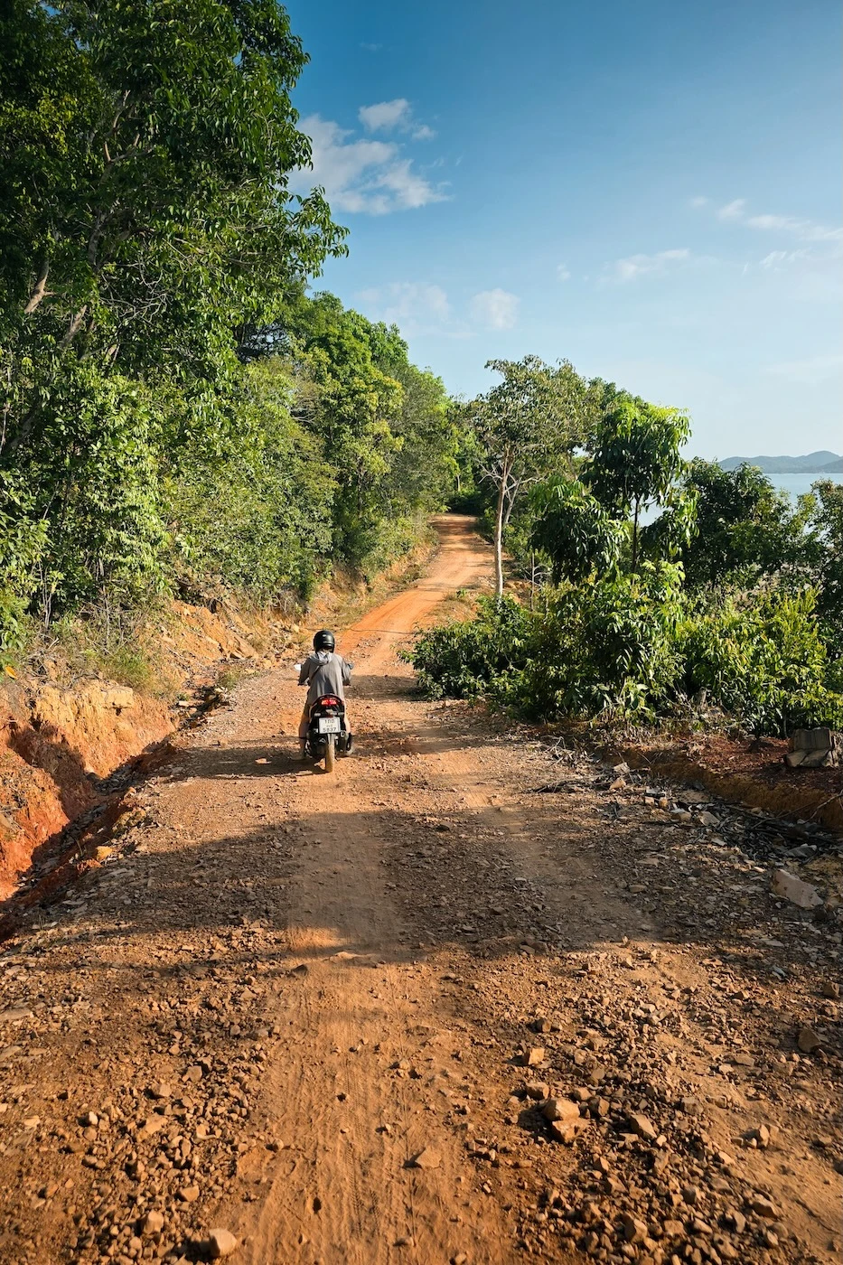 A motorcycle driving along a rough dirt track along the coast of Koh Yao Yai.