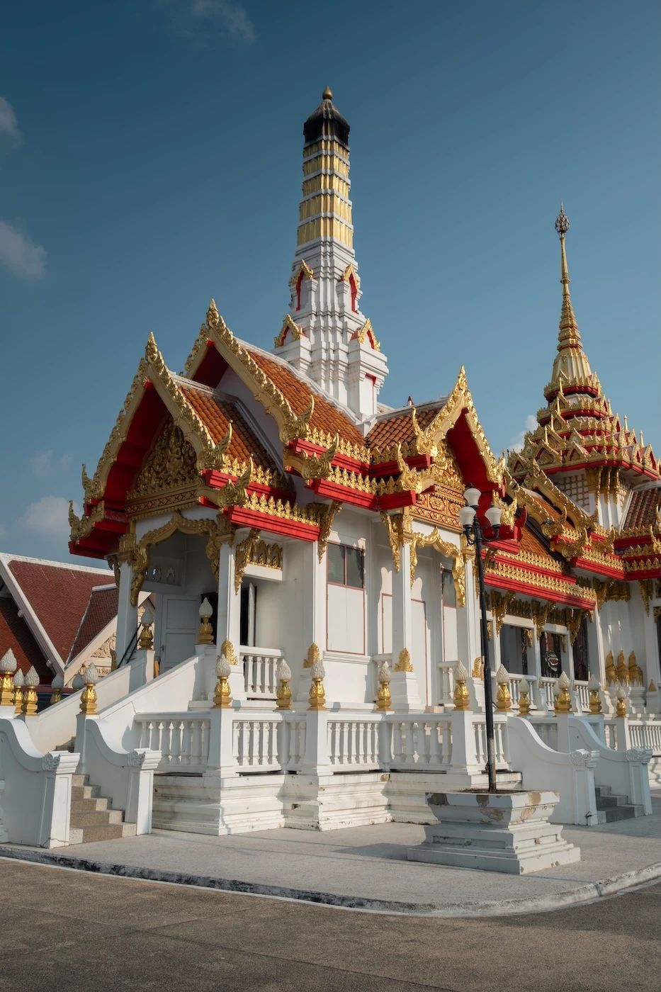 An ornate white temple building with a red and gold roof at Wat Sensanaram.