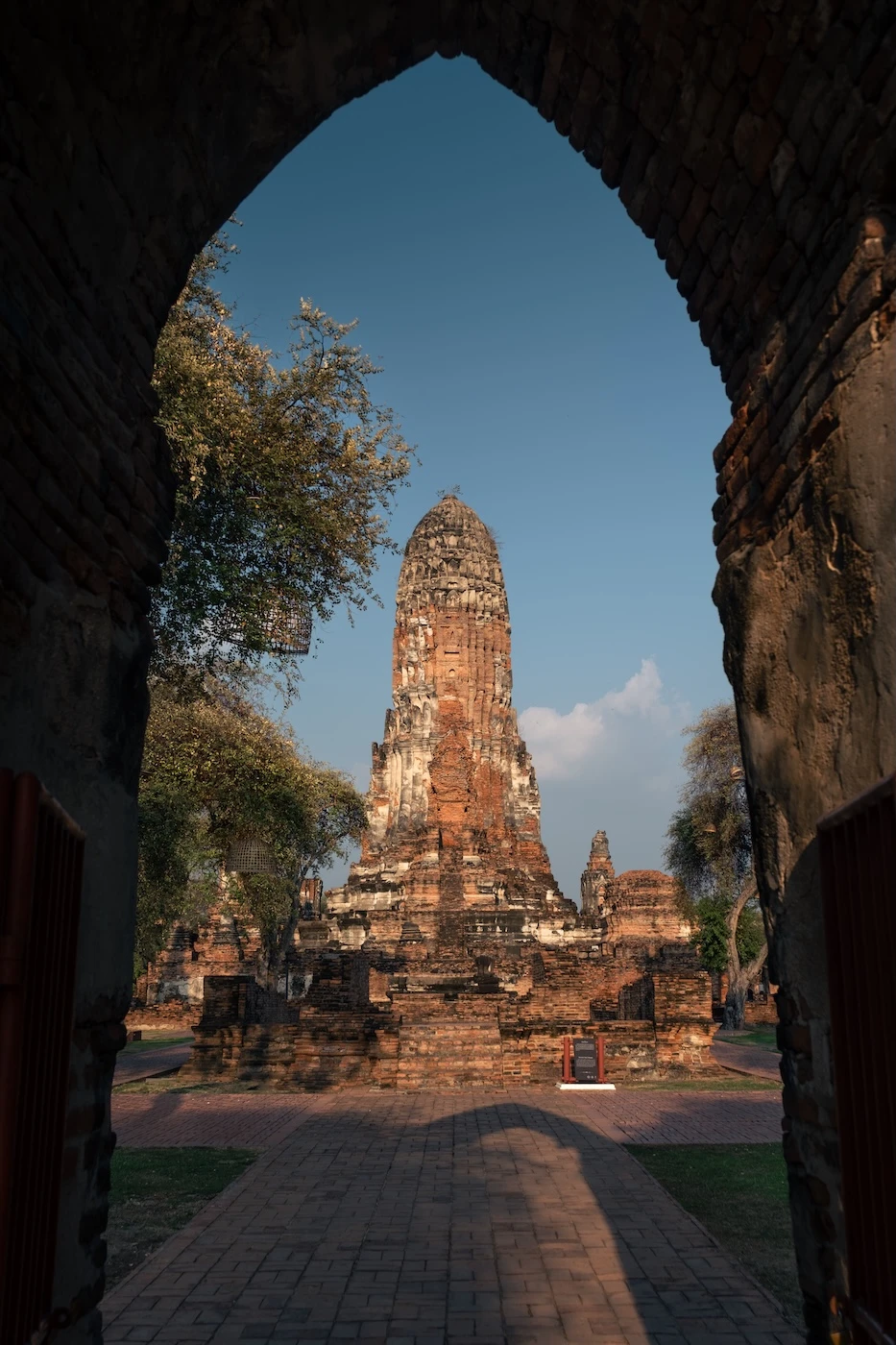 A prang tower seen through an archway at Wat Phra Ram temple ruins in Ayutthaya.