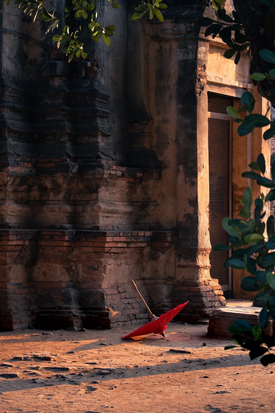A red umbrella laying on the floor of the temple at Wat Chaiwatthanaram at sunset.