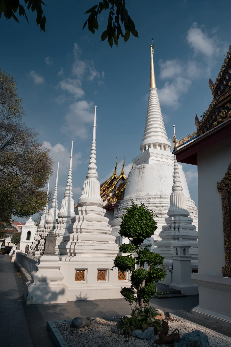 Two rows of gleaming white chedi structures at Wat Suwandaram.