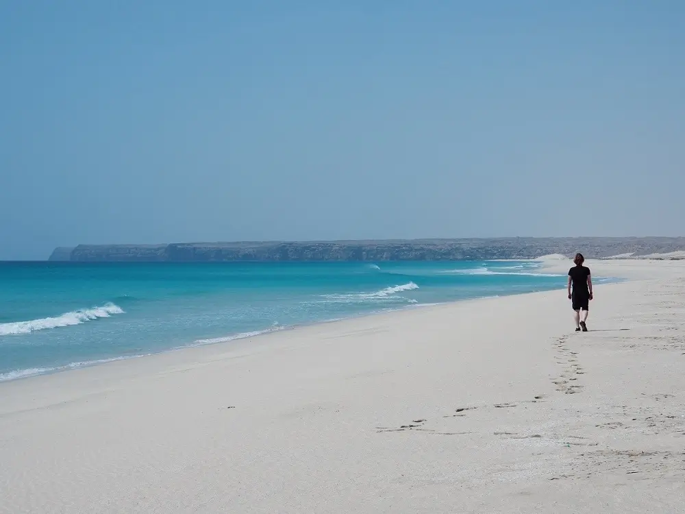 A person walking along the sandy coastline along the large expanse of beach at Ras Madrakah, near Duqm.
