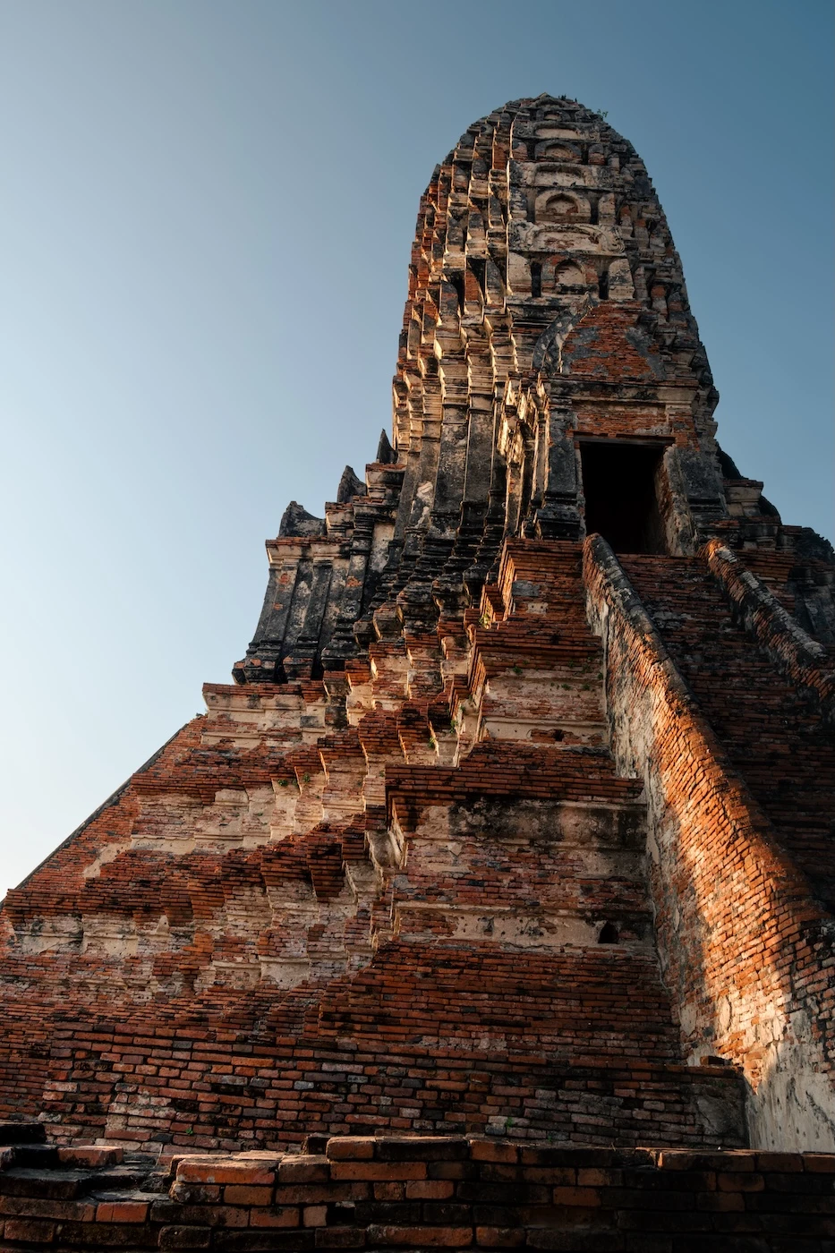 Sunset light on the orange and white layers of bricks at Wat Chaiwatthanaram temple.