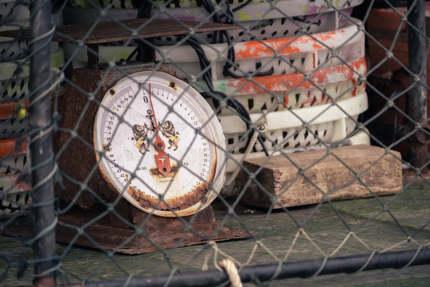 Rusty weighing scales by empty plastic fish baskets on a boat docked at the pier by a fishing village on Koh Yao Yai.