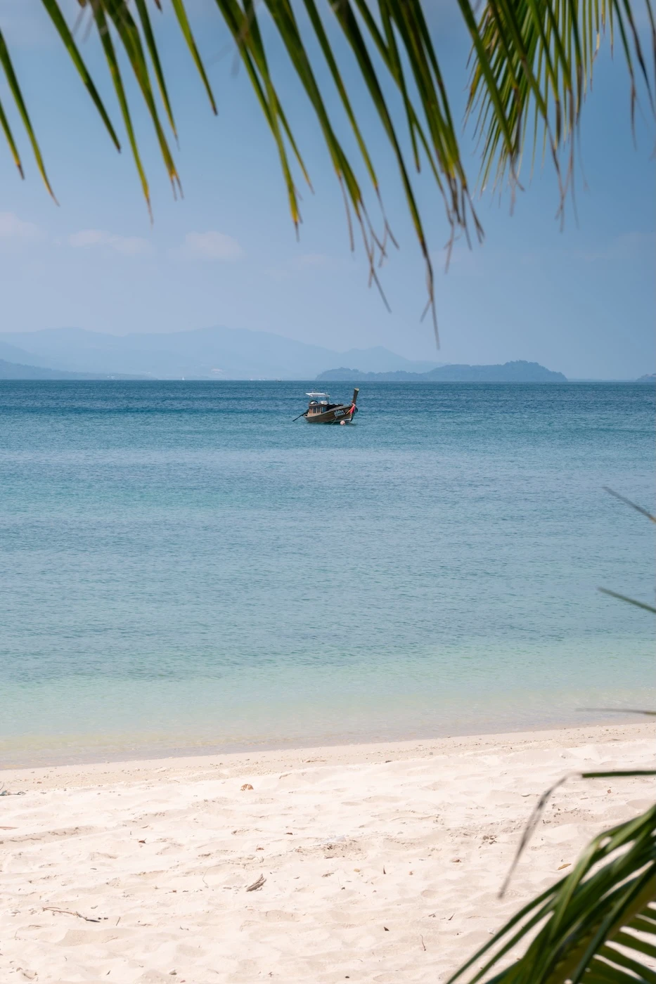 A wooden boat in the calm waters off Lo Chak Beach.