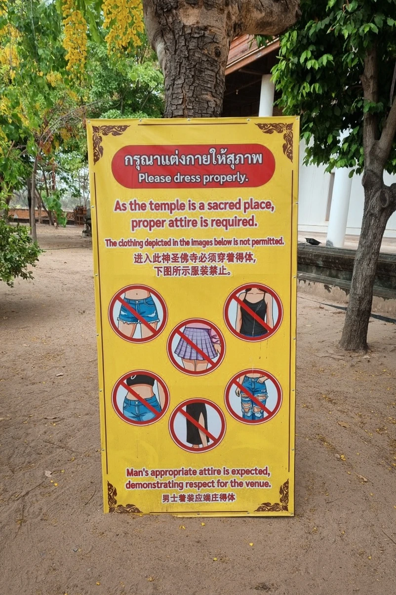 A yellow sign informing of acceptable clothing attire for going into a temple in Ayutthaya.