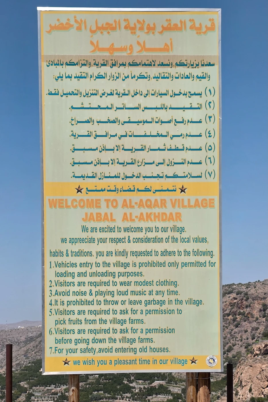 A tourist information sign for visitors to Al Aqar village on Jebel Akhdar, informing in both English and Arabic expected rules to follow.