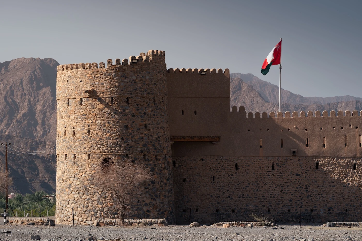 Recently renovated walls at Al Awabi Fort, with an Omani flag flying from the flagpole.