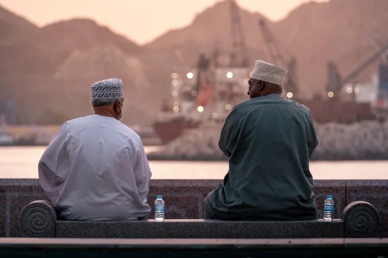 Two Omani residents sat by the corniche in Muscat at sunset.