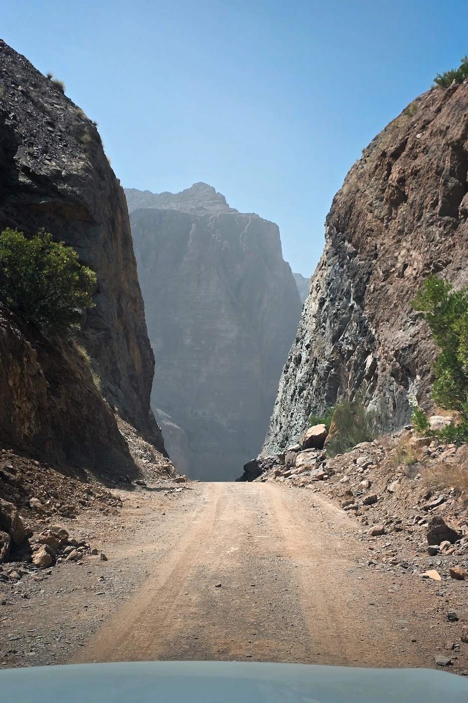 A cutting through the mountainside in Jebel Akhdar with an off-road path leading through it.