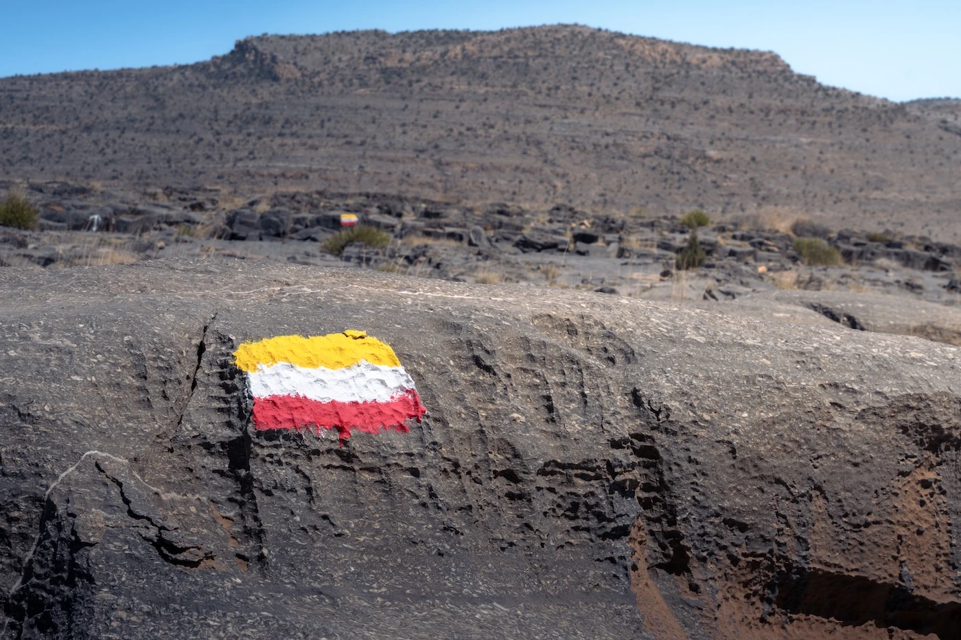 A painted flag consisting of yellow, white and red, used as a trail marker for the W19 hike on Jebel Khdar, Oman.