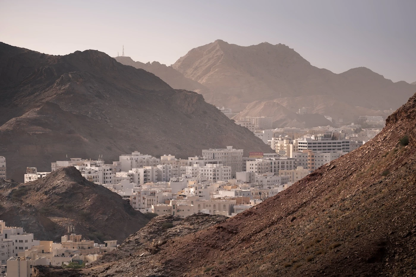 Bright white buildings nestled between rocky hills at Yiti in Oman's capital of Muscat.