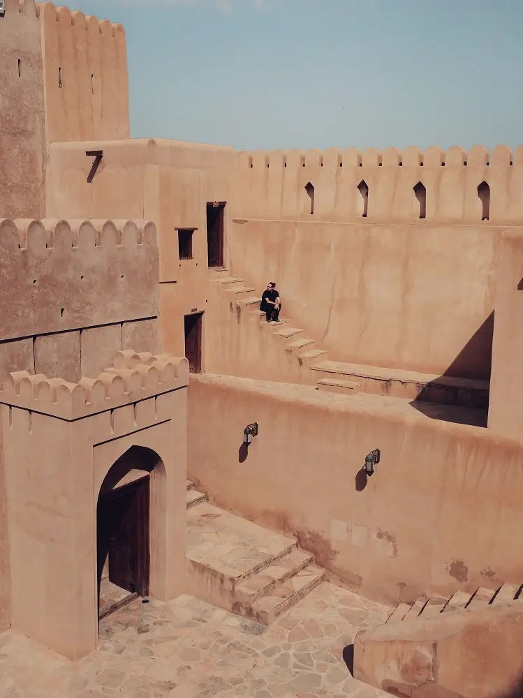 A person sat among the stairs inside the structure of Bahla Fort, Oman.